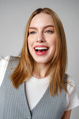 Joyful Young Blonde Woman Smiling against gray background