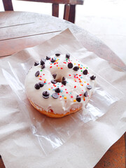 cake with icing. a donut layered with white cream and sprinkled with colorful sprinkles and choco pie. sweet snack. colorful bread