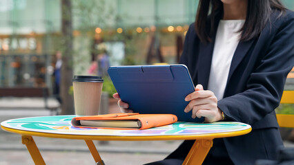 カフェテラスでタブレットを見る女性