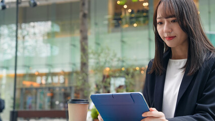 カフェテラスでタブレットを見る女性