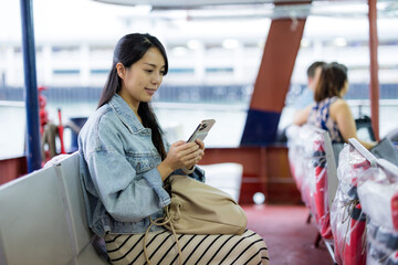 Woman take ferry with her mobile phone in Hong Kong city