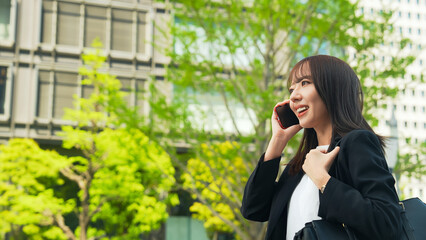 スマホで通話しながら街を歩く女性ビジネスパーソン