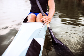 Close up of canoeist sitting in canoe holding paddle, in water. Concept of canoeing as dynamic and...