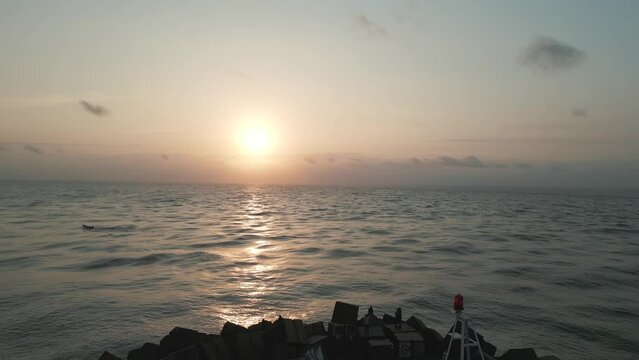 Aerial view of a stunning sunset over the Gulf of Mexico, panning backward to reveal the Playa Miramar Madero Lighthouse.