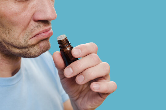 Sad sick man with smell blindness sniffing bottle of essential oil. Smell loss screening: Medical practitioner administers anosmia test