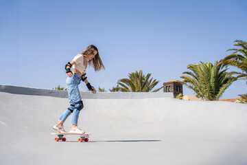 Young Woman Riding Skateboard Down Ramp