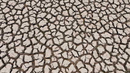 From above, a drone unveils a landscape scorched by drought, its cracked surface echoing the thirst...