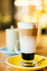 Close up shot of coffee with milk and caramel on a wooden table at coffee shop.