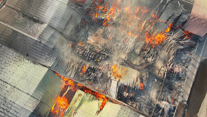 Aerial perspective unveils a harrowing scene, a raging inferno engulfs an industrial complex....