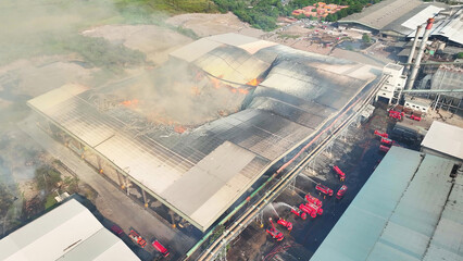Amidst chaotic flames, fire trucks battle furiously, dousing torrents of water onto the scorched...