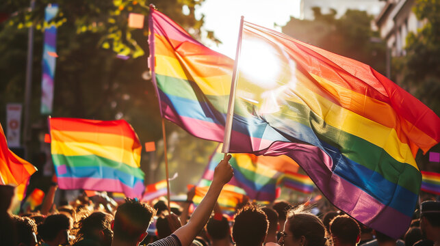 Pride Parade Celebration with Rainbow Flags. Vibrant scene at a pride parade showing a crowd waving rainbow flags under the bright sunlight, celebrating diversity and freedom. LGBTQ
