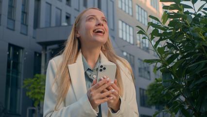 Portrait excited surprised Caucasian woman businesswoman business lady girl winner read good news on mobile phone enjoy success outdoors celebrating victory win online bet using smartphone on street