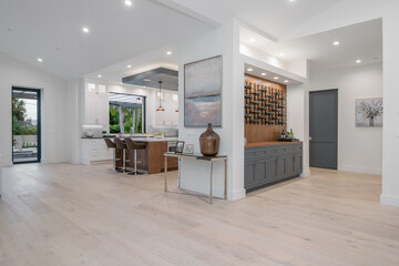 White kitchen with island and multiple chairs in a modern new construction home in Los Angeles