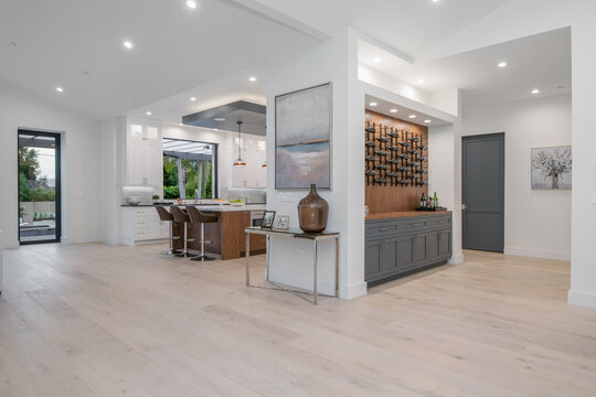 White kitchen with island and multiple chairs in a modern new construction home in Los Angeles