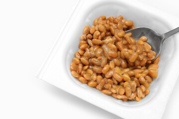 Close up of Natto or Fermented Soybean with stainless spoon isolated on white background....
