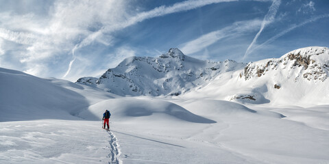 Man ski touring towards snowcapped mountains