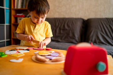 Boy playing cooking game with toy kitchen at home
