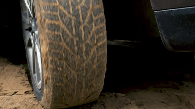 Car ESP system engaged as vehicle navigated through sandy terrain. Vehicle spinning wheel close up. Rotating tyre on dirty road. Automobile offroad