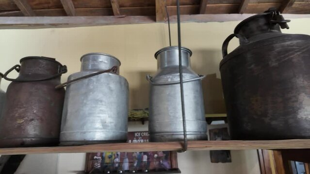 4k video footage of The container for milking cow's milk made of aluminum metal placed in a row on a wooden rack. Old rusty milk pail. Concept for cattle farm and rustic.