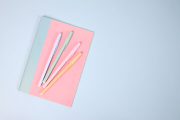 Pastel book and pens on blue background with copy space. Back to school stationery concept.