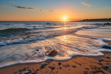 Golden sunset reflecting on waves and pebbles on sandy beach