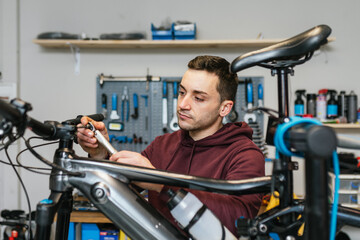 The mechanic uses an Allen ratchet wrench on the handlebar of an electric mountain bike.