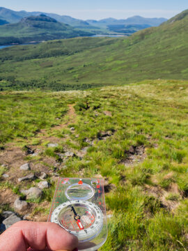 UK, Scotland, Hand of male hiker using navigational compass in Cairngorm Mountains