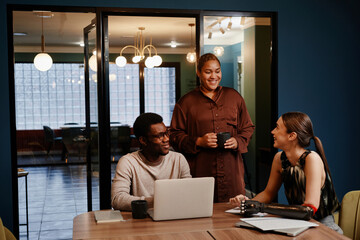 Smiling diverse colleagues discussing at conference table in office