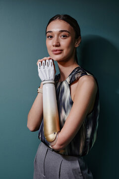 Smiling woman with bionic arm standing in front of green wall