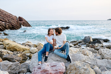 Two People Sitting on Rocks by the Ocean