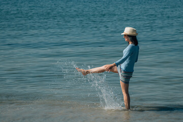 young woman playing with water on the beach
