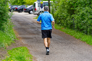 Middle aged male jogger on rural road at Swiss City of Zürich on a spring Sunday. Photo tkaen May 5th, 2024, Zurich, Switzerland.