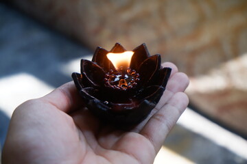 The light on a lotus pray candle held by a hand