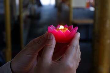 The light on a lotus pray candle held by hands