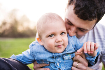 Father holding little toddler boy playing, having fun during warm spring day. Father's day concept.