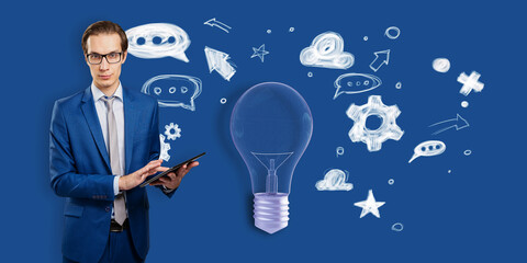 Attractive thoughtful young businessman with tablet and creative light bulb sketch with icons on...