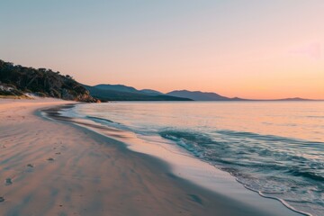 Serene sunrise over secluded sandy beach with mountains