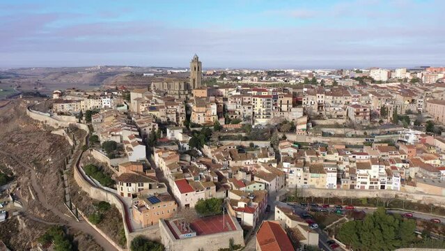 Shot of province Cervera, ancient European city located on hilly area in Segarra area. Dron aerial view of small compact city, winding city wall, twisted road- mountain serpentine