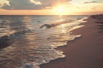 Golden sunrise reflecting on gentle ocean waves and sandy beach