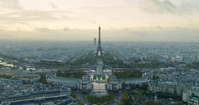 Beautiful view of famous Eiffel Tower in France with magical morning cloud and fog. Wide establishing aerial drone fly over seine river in paris city center, best travel destination landmark in Europe