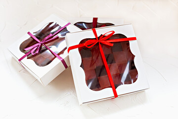 Three sophisticated white gift boxes with clear windows displaying assorted colorful marmalades,...