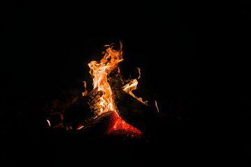 A campfire closeup, burning thick wooden logs