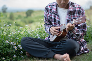 Obraz premium Asian preteen boy playing ukulele and acoustic guitar at home, lifestyle and hobby of children concept.