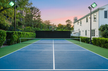 Tennis court outdoors surrounded by trees by a new construction home in Encino, California