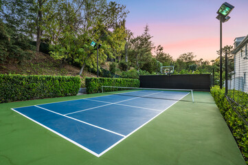 Tennis court outdoors surrounded by trees by a new construction home in Encino, California