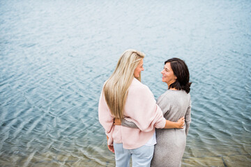 Adult daughter spending time with her mother. Mom and daughter outdoors, on walk by reservoir, lake...