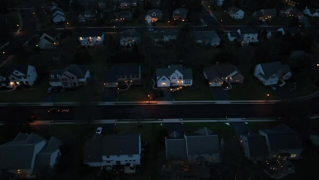 American neighborhood at night. Large, upscale, expensive two story houses in  USA suburb at dusk. Aerial truck shot with a car driving on housing development street.