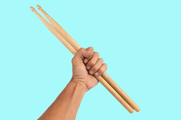 Black male hand holding wooden Drum sticks isolated on cyan background