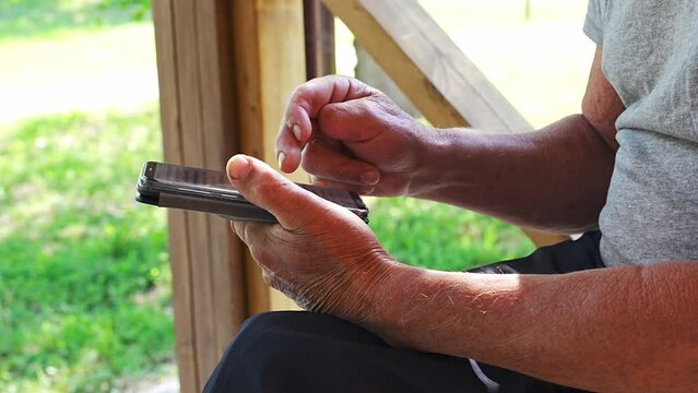 Injured hands of an elderly man with a smartphone. Elderly and disabled people with modern gadgets. amputated fingers. 