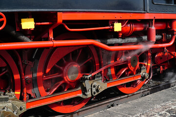 Black and red iron wheels with drive rods of the traditional steam train on the narrow-gauge...